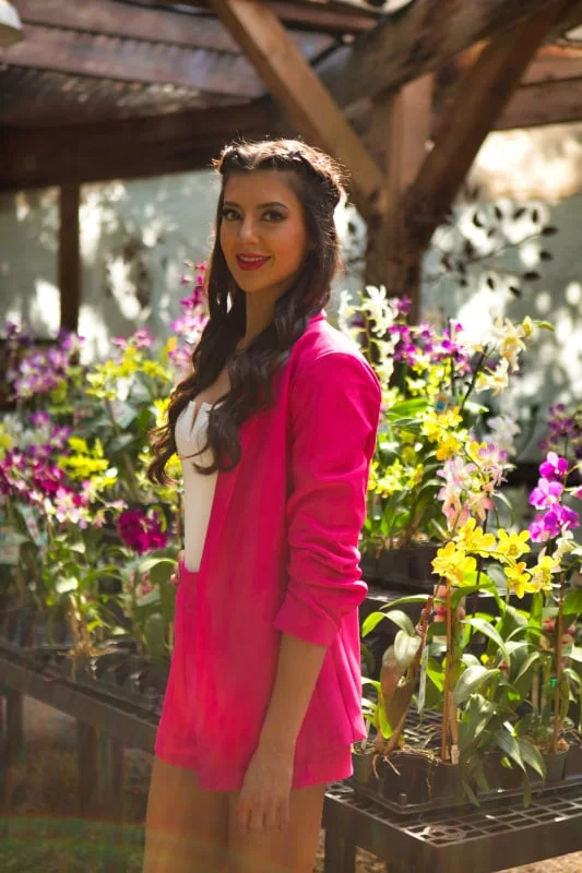 Jasmine in a pink jacket among orchids in a greenhouse